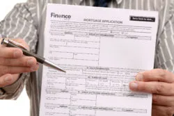 A man holds out a mortgage application and a pen.