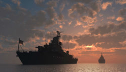 Two Navy ships sail in the evening.