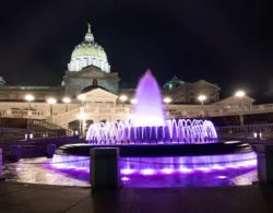 Lighting illuminates the fountain and Pennsylvania capitol.