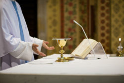 A priest says mass while standing at an altar.