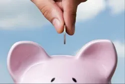Hand placing quarter in piggy bank