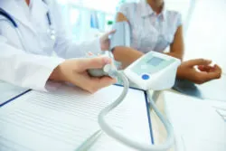 A physician takes a patient's blood pressure.