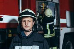 Two firefighters next to a fire truck