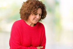 A woman holds her stomach in pain.