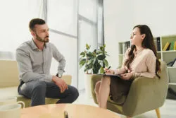 A woman counsels a man in an office.