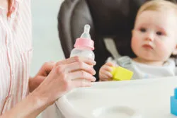 A woman prepares a bottle for a baby.