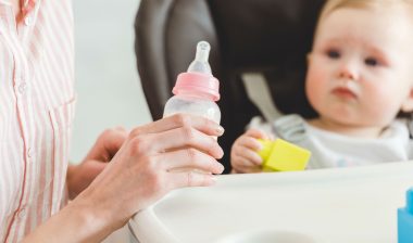 A woman prepares a bottle for a baby.