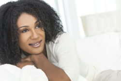 A smiling woman lies on a couch.