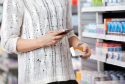 A woman checks her smartphone while shopping.