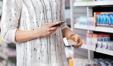 A woman checks her smartphone while shopping.
