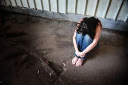 A woman sits alone with her head on her knees.