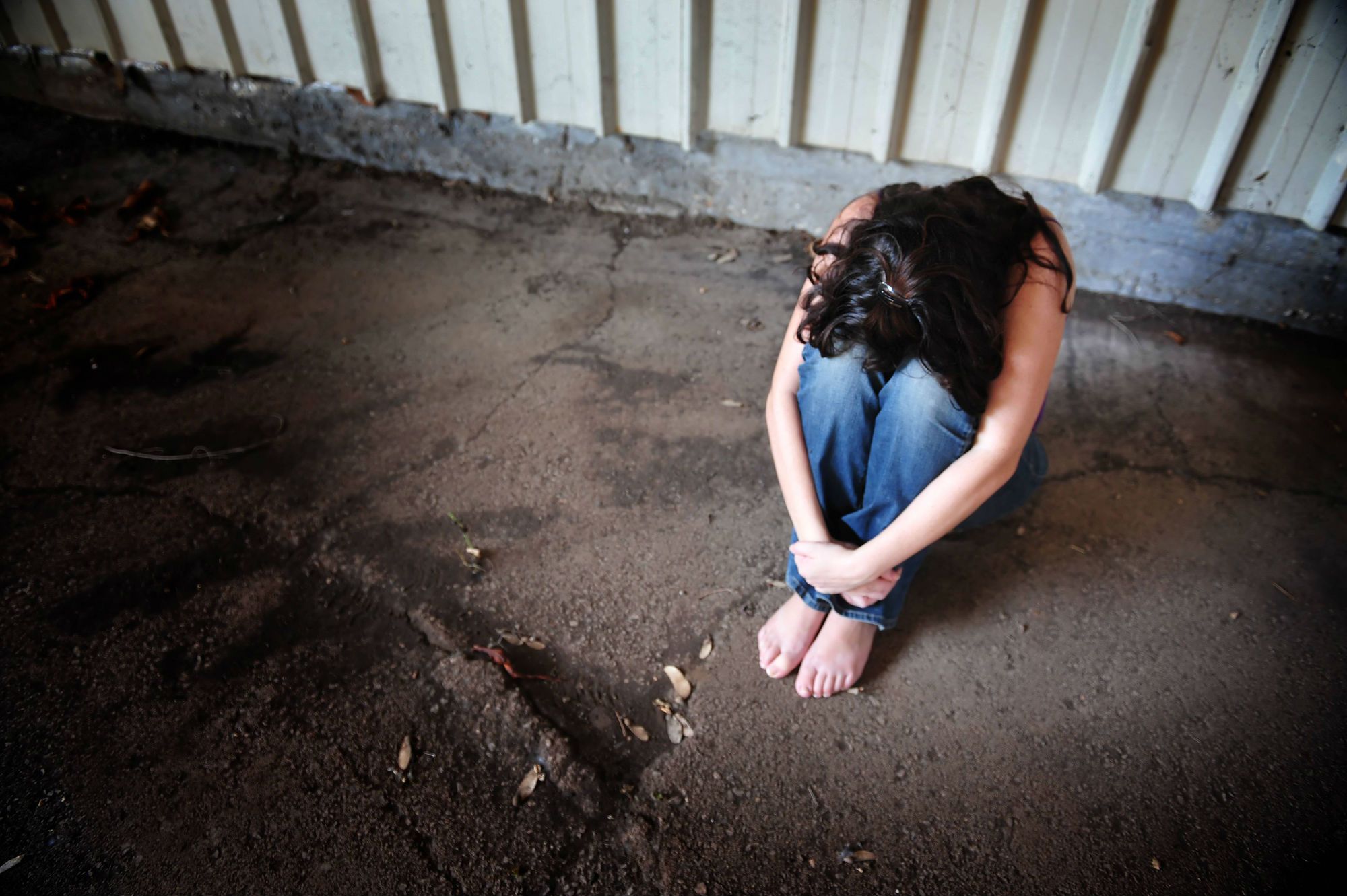 A woman sits alone with her head on her knees.