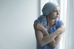 Young woman with cancer looking out of a window