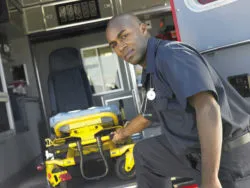 An EMT takes a gurney out of an ambulance