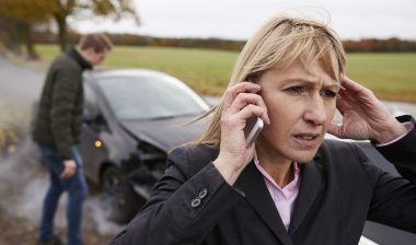 A woman makes a phone call after a car accident.