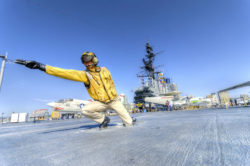 A catapult officer directs a pilot to take off.