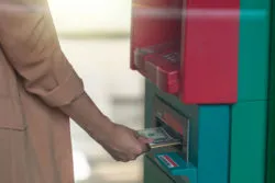 A woman takes cash from an ATM.