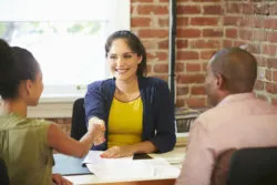 A couple shakes hands with a financial advisor.
