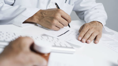 Doctor in labcoat writing a prescription