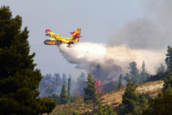 Fire fighting airplane drops water on forest fire.