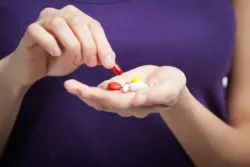 A woman holds a handful of supplements.