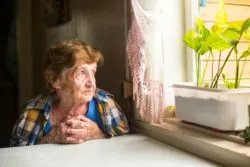 Lonely old woman looking out of window