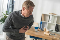Middle aged man feeling heart pain in office