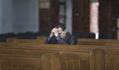 A man prays in a church.