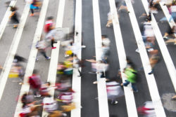 Pedestrians walk in a large crosswalk.