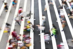 Pedestrians walk in a large crosswalk.