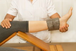 A physical therapist bends a woman's knee.