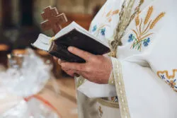 Priest holding bible and cross