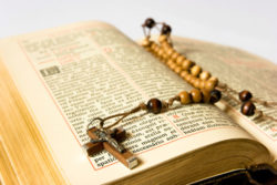 A rosary lies on an open bible.