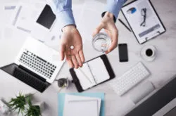 A person at a desk takes a pill.