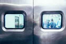 Team of surgeons operating, viewed through operating room door.