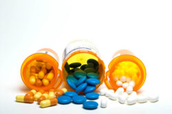Three medication bottles spilling out pills