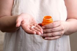 Woman holding diabetes pill in one hand