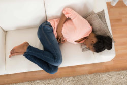 Woman in pain lying on sofa