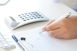 Hand with calculator writing on paper