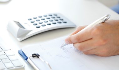Hand with calculator writing on paper