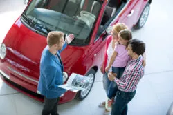 A salesman shows a car to a family.
