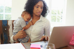 Concerned mom on computer with sleeping baby