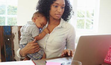 Concerned mom on computer with sleeping baby
