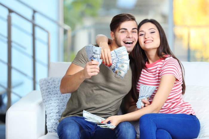 couple holding money from settlement checks