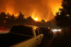 A wildfire burns behind a truck.