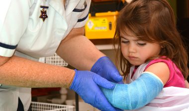 A nurse helps a girl with a broken arm.