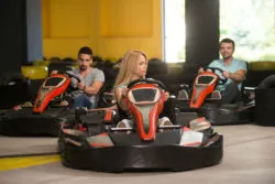 Three riders ride in a go-kart park.