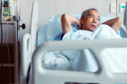 A man lies in a hospital bed.