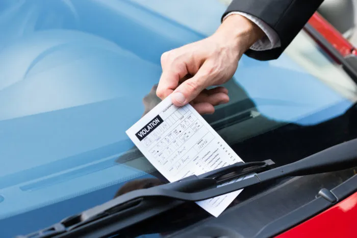 Close up of a parking ticket on a windshield.