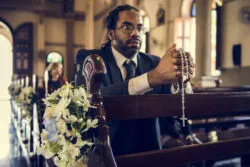 A man prays with a rosary in church.